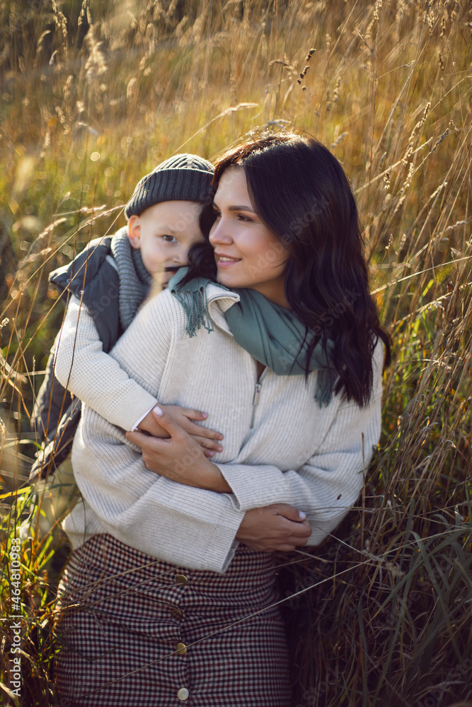 mother and her son are standing in a field with dry grass at sunset mother and her son are standing in a field with dry grass at sunset