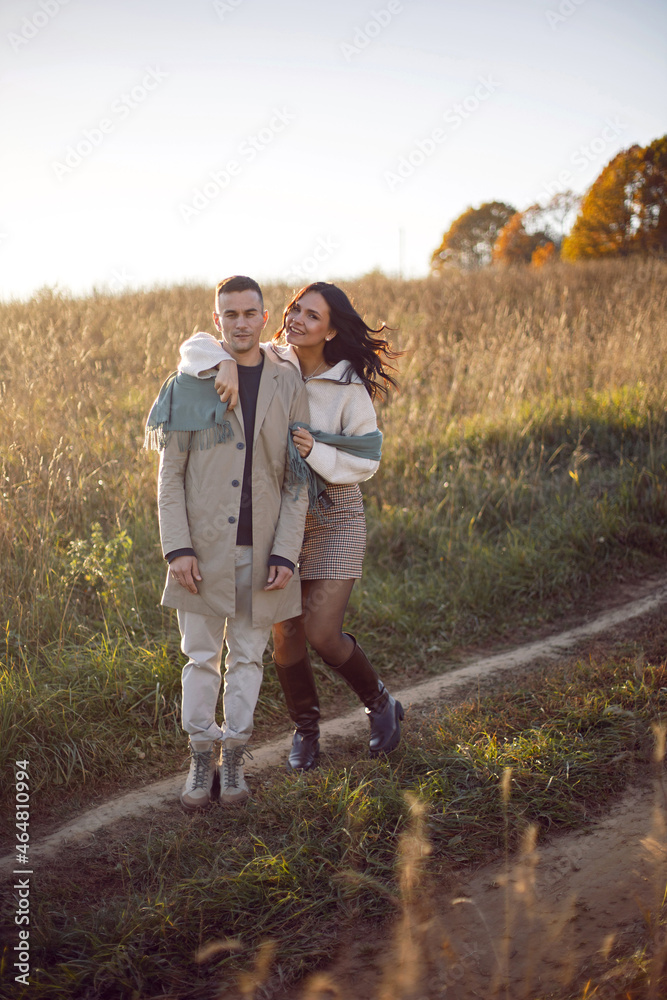 couple of a man with a woman in a field with dry grass at sunset