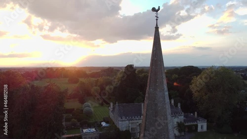 dramatic skies and rooster on church of old roof in Fairford, Cotswold, England, UK. Drone aerial bird eye view shot