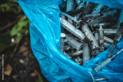 garbage bag with used disposable medical syringe leaved by drug addicted in park