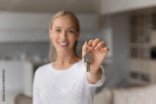 Close up smiling young woman holding keys in hands, celebrating moving into own apartment. Joyful millennial female homeowner feeling excited of purchasing first dwelling, real estate concept.