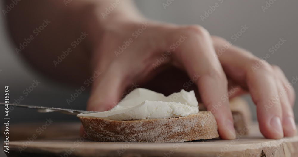 man hand spreading cream cheese on dark ciabatta man hand spreading cream cheese on dark ciabatta