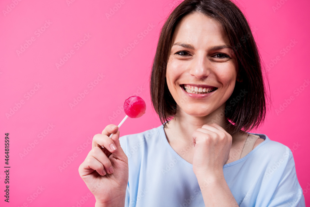 Young woman with sensitive teeth eating sweet lollipop on color background Young woman with sensitive teeth eating sweet lollipop on color background