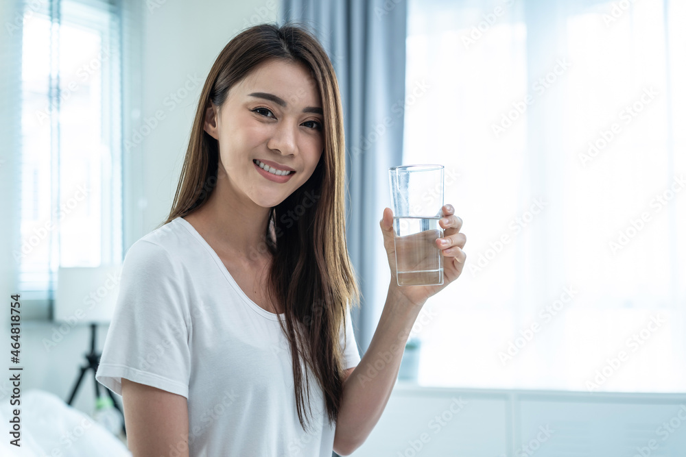 Portrait of Asian attractive woman holding a glass of water in bedroom. Portrait of Asian attractive woman holding a glass of water in bedroom.