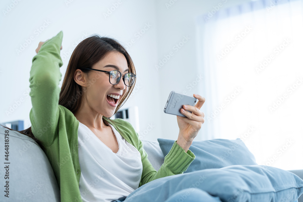 Asian woman wear eyeglasses play mobile game on smartphone at home. Asian woman wear eyeglasses play mobile game on smartphone at home.