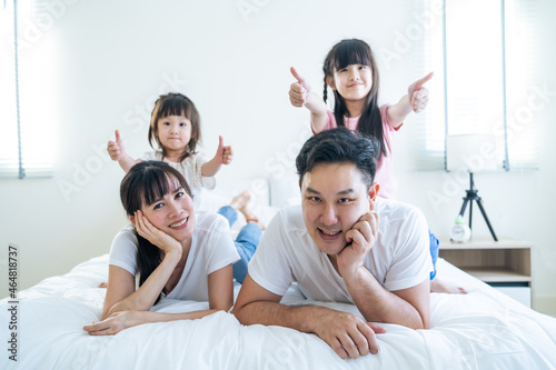 Portrait of Asian happy family smile and look at camera on bed at home. 