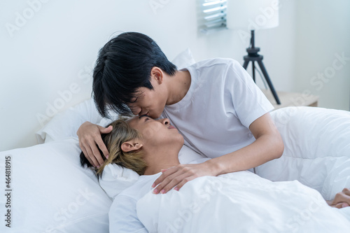 Asian attractive gay kiss boyfriend's forehead to wake up from sleep.