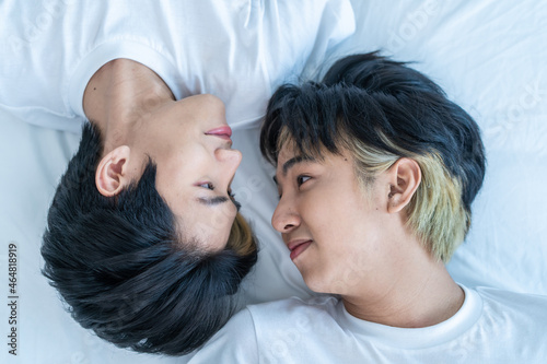 Asian happy man gay family lying down on bed and look at each other.