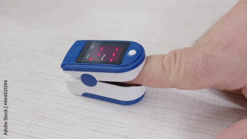 Portable pulse oximeter with measurement indicator on display screen showing level of oxygen in blood and heartbeat of person close-up. Diagnostics, treatment and health control. Portable pulse oximeter with measurement indicator on display screen showing level of oxygen in blood and heartbeat of person close-up. Diagnostics, treatment and health control.