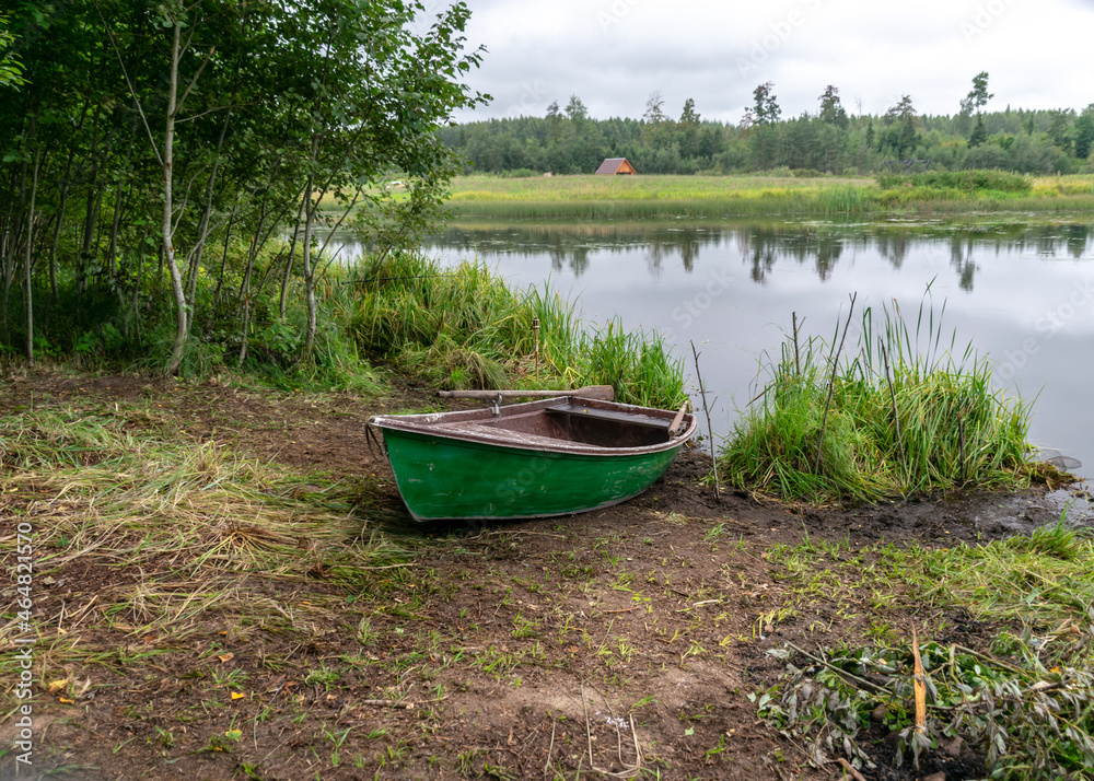 lake shore and boat, calm lake water surface, tree reflections, cloudy day, fishing concept