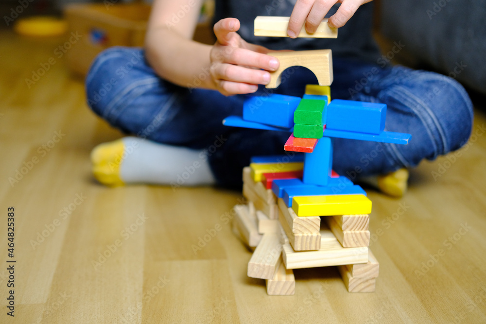 child, kid plays with colored wooden cubes, builds houses and rockets, the concept of the development of creativity, fine motor skills, patience and perseverance