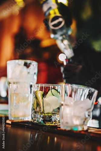 hands of a bartender with black gloves making cocktail on a bar counter.