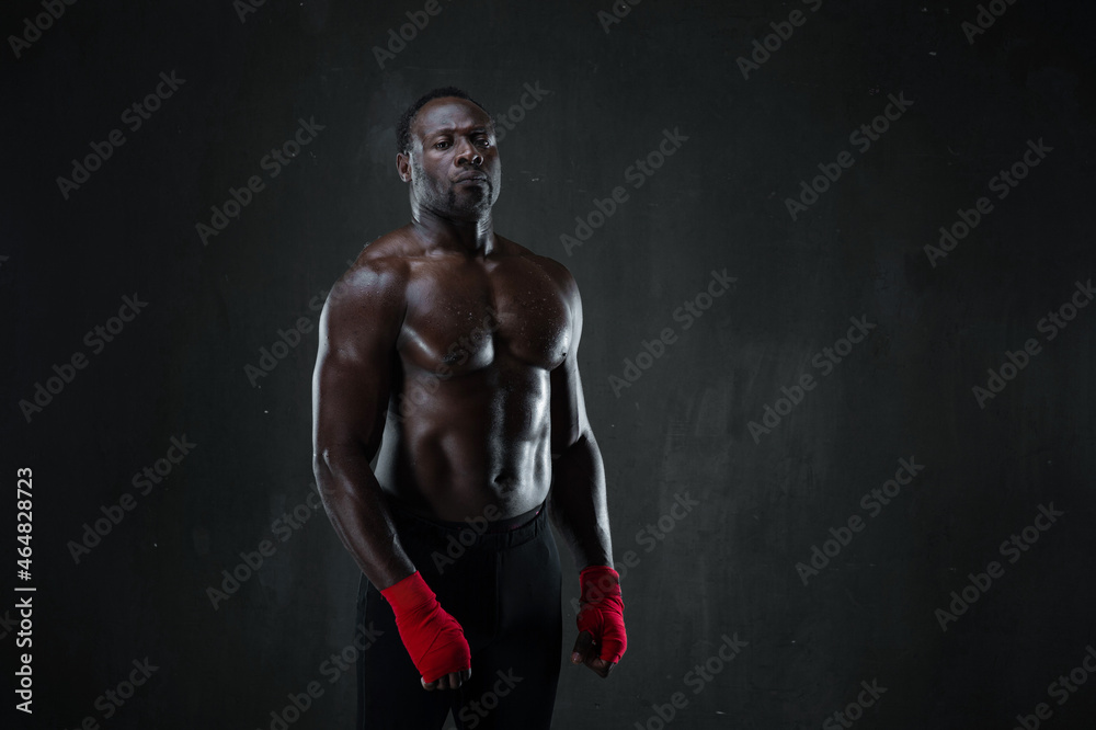 African american muscular athlete over black background. Sporty man in boxing style. Strength, sport and motion project.