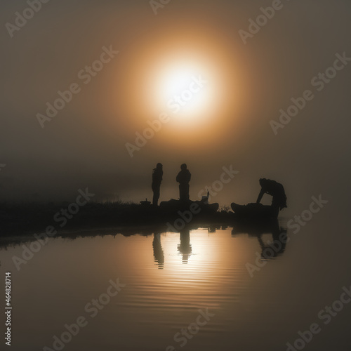 Fishermen prepare their essentials a midst a foggy sunrise.