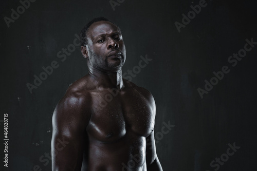 African american muscular athlete over black background. Sporty man in boxing style. Strength, sport and motion project.