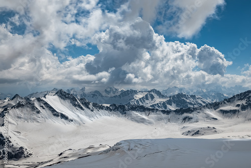 Mountain clouds over beautiful snow-capped peaks of mountains and glaciers. View at the snowy mountains.