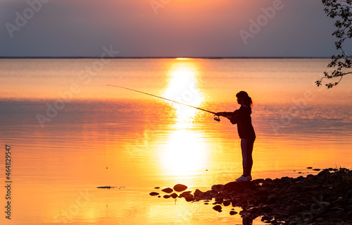 Woman fishing on Fishing rod spinning in Finland at sunset.