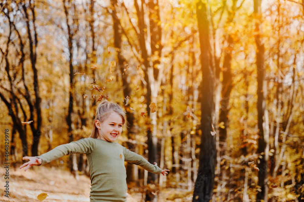 Small little girl is playing with yellow leaves in autumn forest or garden Small little girl is playing with yellow leaves in autumn forest or garden