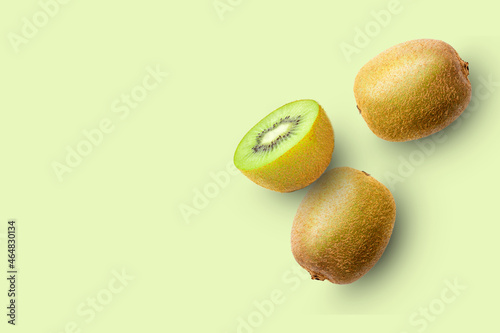 Kiwi fruits and cut in half sliced isolated on green color background. Top view. Flat lay.