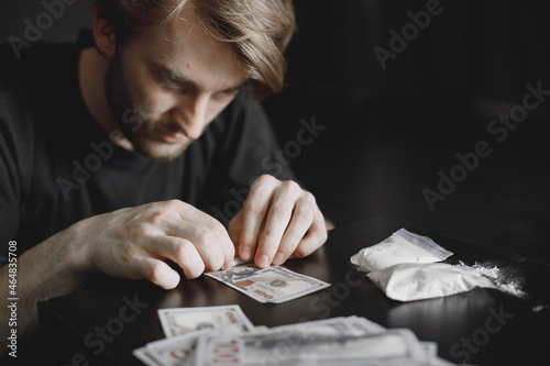 фотографія Young addicted man taking cocaine with dollar