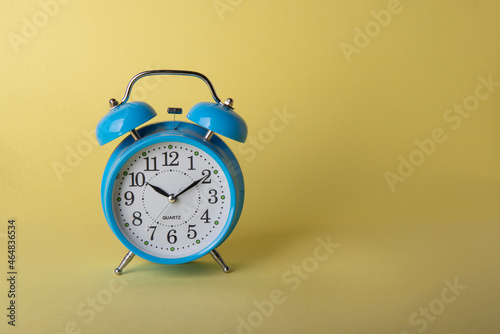 Blue retro alarm clock isolated on yellow