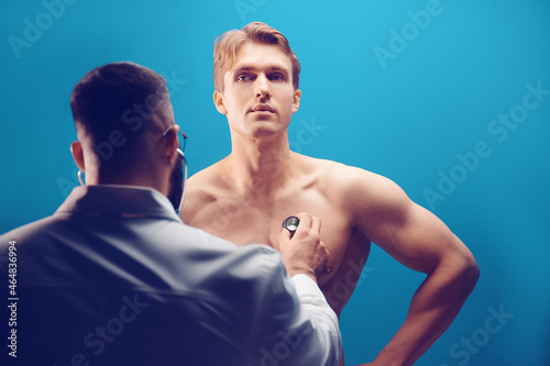 Doctor listening with stethoscope to patient in medical office 