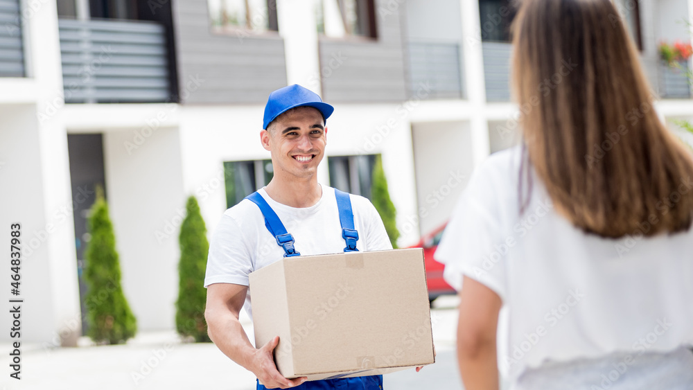 Young courier delivering goods to a young woman at home Young courier delivering goods to a young woman at home