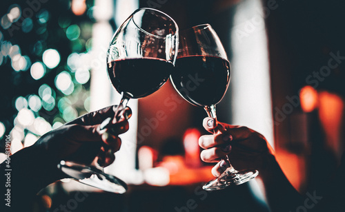 Young women hands holding glasses of red wine and clinking wine glasses in cafe or restaurant