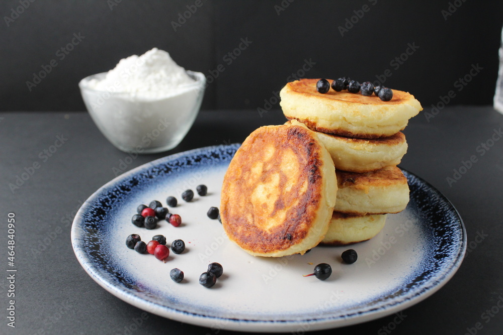 breakfast pancakes cheesecakes are stacked slide on a plate with blueberries blueberries cherries. Traditional breakfast Russian Slavic in the background is egg flour. Cooking breakfast