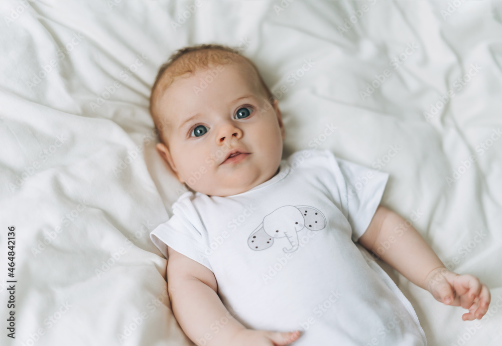 Cute baby girl 2-4 month on bed with white linen, natural tones, selective focus Cute baby girl 2-4 month on bed with white linen, natural tones, selective focus