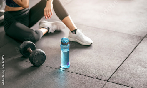 Fitness woman breaking relax after training with dumbbell at gym.