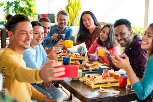 Friends group drinking cappuccino at coffee bar restaurant - People smiling and toasting juice while taking a selfie - Friendship concept with happy men and women at breakfast room.