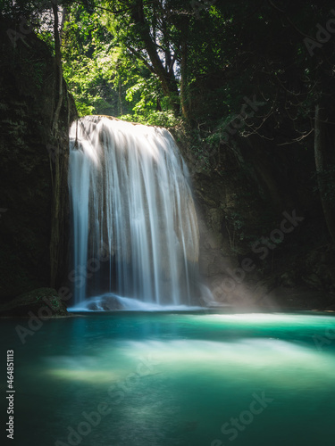 Scenic view of Erawan Waterfall. Breathtaking smooth flowing white stream with epic sunbeam shine down to turquoise pond in lush rainforest. Kanchanaburi, Thailand. Long exposure.