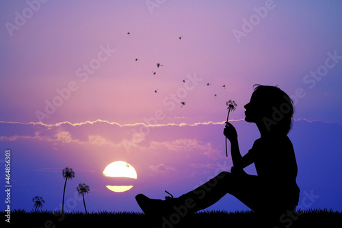 little girl blows the dandelion at sunset
