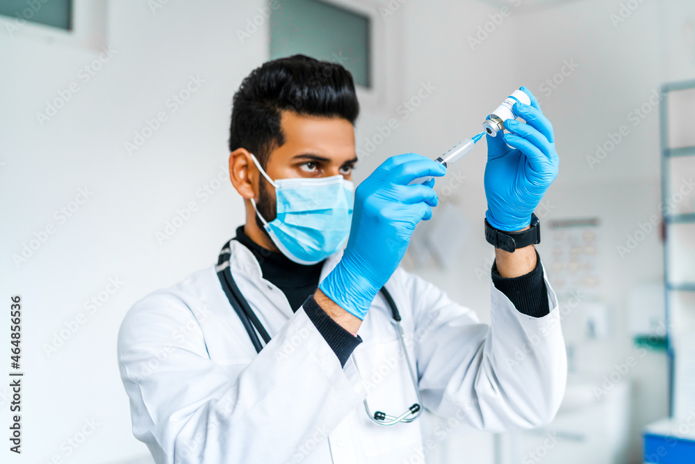 An Indian male doctor in a protective mask takes an injection of coronavirus, before vaccinating the patient, a safe vaccine, injection An Indian male doctor in a protective mask takes an injection of coronavirus, before vaccinating the patient, a safe vaccine, injection