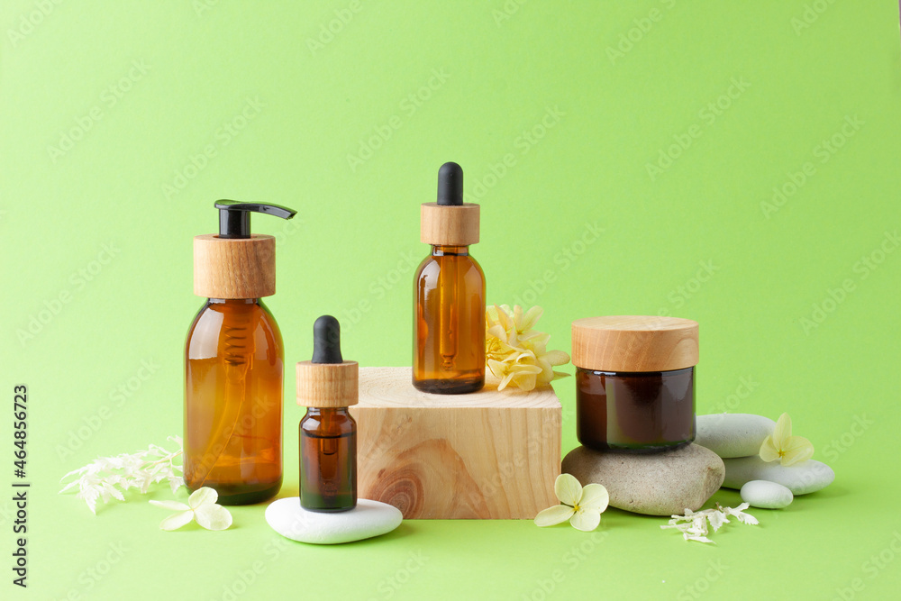 Cosmetic skin care products with wood podium and flowers, stone on green background. Close up, copy space Cosmetic skin care products with wood podium and flowers, stone on green background. Close up, copy space