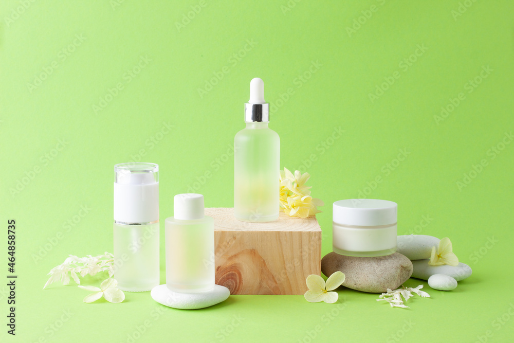Cosmetic skin care products with wood podium and flowers, stone on green background. Close up, copy space Cosmetic skin care products with wood podium and flowers, stone on green background. Close up, copy space