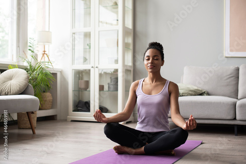 Woman meditating and practicing yoga at home. African american girl relaxing. Recreation, self care, yoga training, fitness, breathing exercises, meditation, relaxation, healthy lifestyle concept