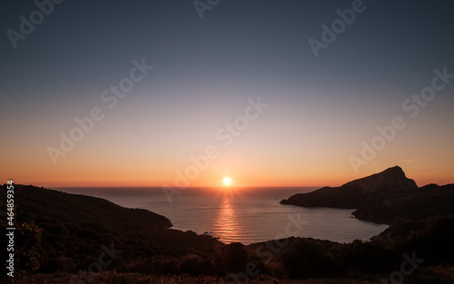 Sun setting over the Genoese tower of Tour de Turghiu sitting on Capo Rosso on the west coast of Corsica