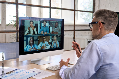 Corporate leader manager leading videoconference with diverse team business people having digital group video call conference working in office at online virtual meeting on pc computer. Over shoulder
