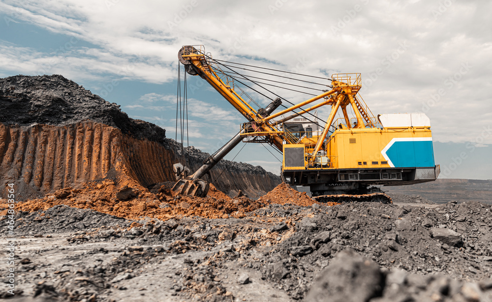 Large quarry dump truck. Big yellow mining truck at work site. Loading coal into body truck. Production useful minerals. Mining truck mining machinery to transport coal from open-pit production Large quarry dump truck. Big yellow mining truck at work site. Loading coal into body truck. Production useful minerals. Mining truck mining machinery to transport coal from open-pit production