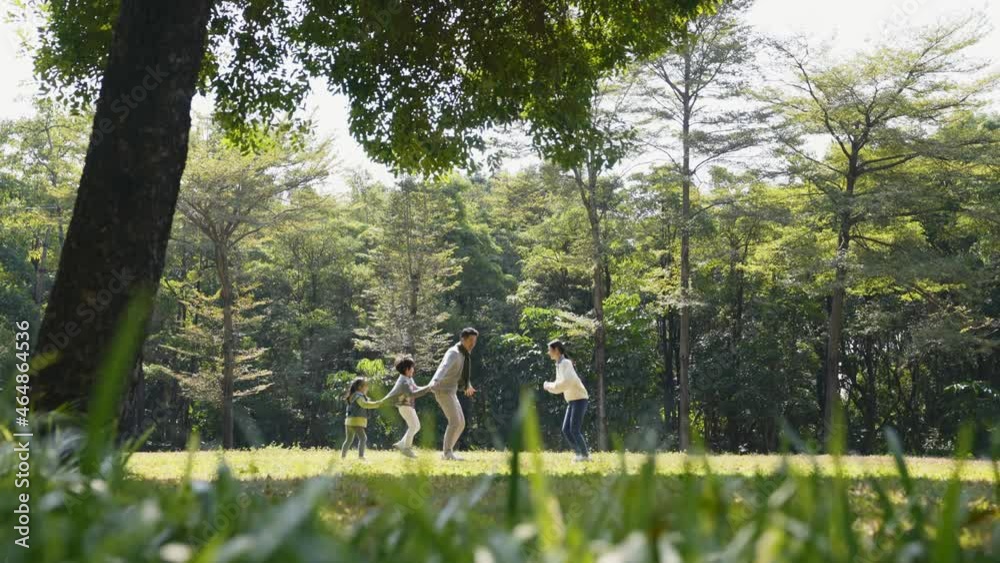 asian family with two children having fun playing outdoors in city park