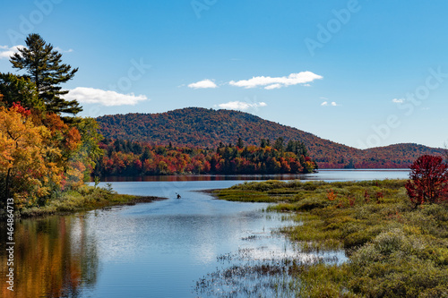 Autumn landscape in the Adirondack Mountains with a canoe traveling into Lewey Lake