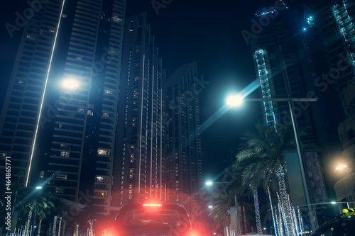 Night city lights. High modern skyscrapers buildings and red lights from car. Urban background.