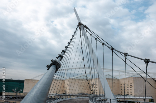 Steel structure walking bridge with train station in the background.