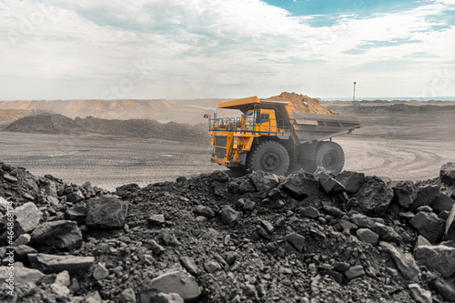 Large quarry dump truck. Big yellow mining truck at work site. Loading coal into body truck. Production useful minerals. Mining truck mining machinery to transport coal from open-pit production photo