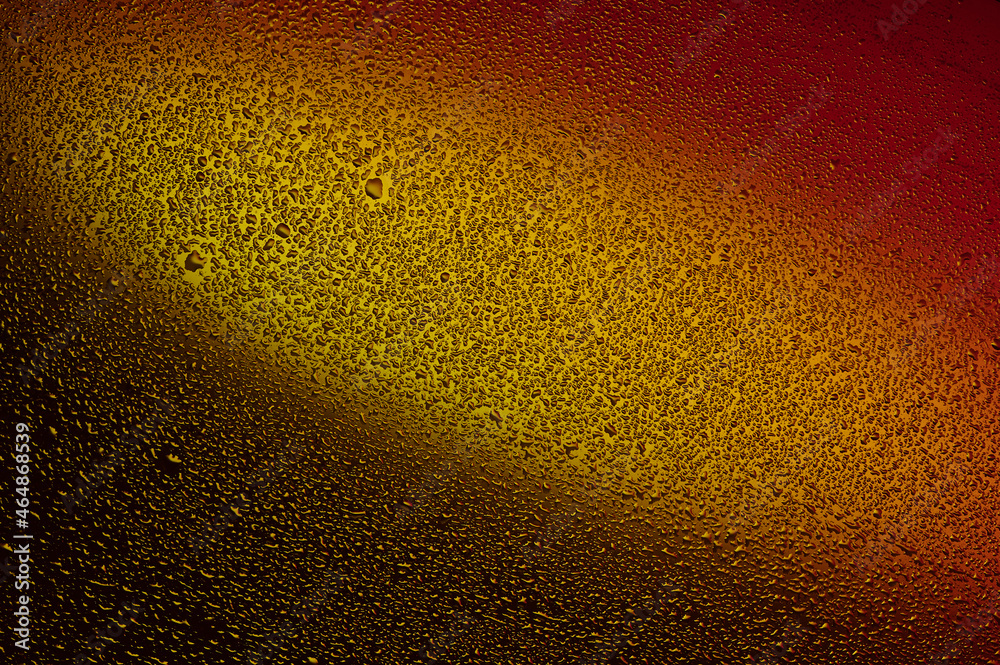 Water drops on black glass. Background illuminated with red and yellow light. Water drops on black glass. Background illuminated with red and yellow light.