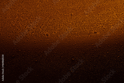 Water drops on black glass. Background illuminated with orange ​light.