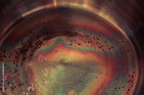Macro photo of corrosion and oxidation of metal. Bottom of the pan with rainbow steel colouration. Aged rusty industrial background, patina at damaged steel.