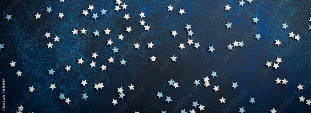 White and blue small stars of sweets on a dark blue concrete or stone background. Selective focus. Christmas composition. Top view. Copy space White and blue small stars of sweets on a dark blue concrete or stone background. Selective focus. Christmas composition. Top view. Copy space